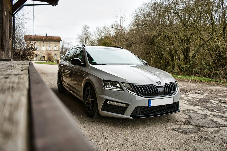 Silberner Skoda Octavia Combi, schräg von vorne, neben einem Holzgeländer