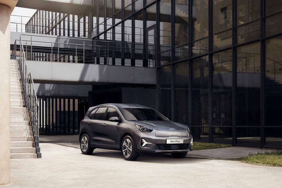 Grauer Kia e-Niro, schräg von vorne, vor einem modernen Gebäude