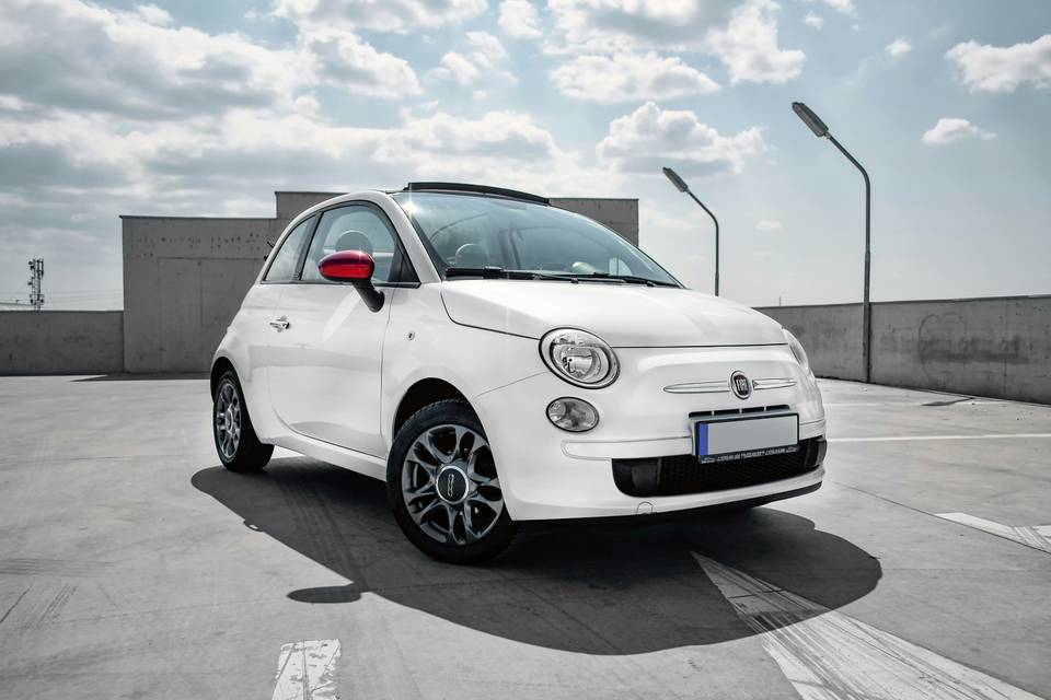Weisser Fiat 500C mit offenem Stoffverdeck auf einem Parkdeck