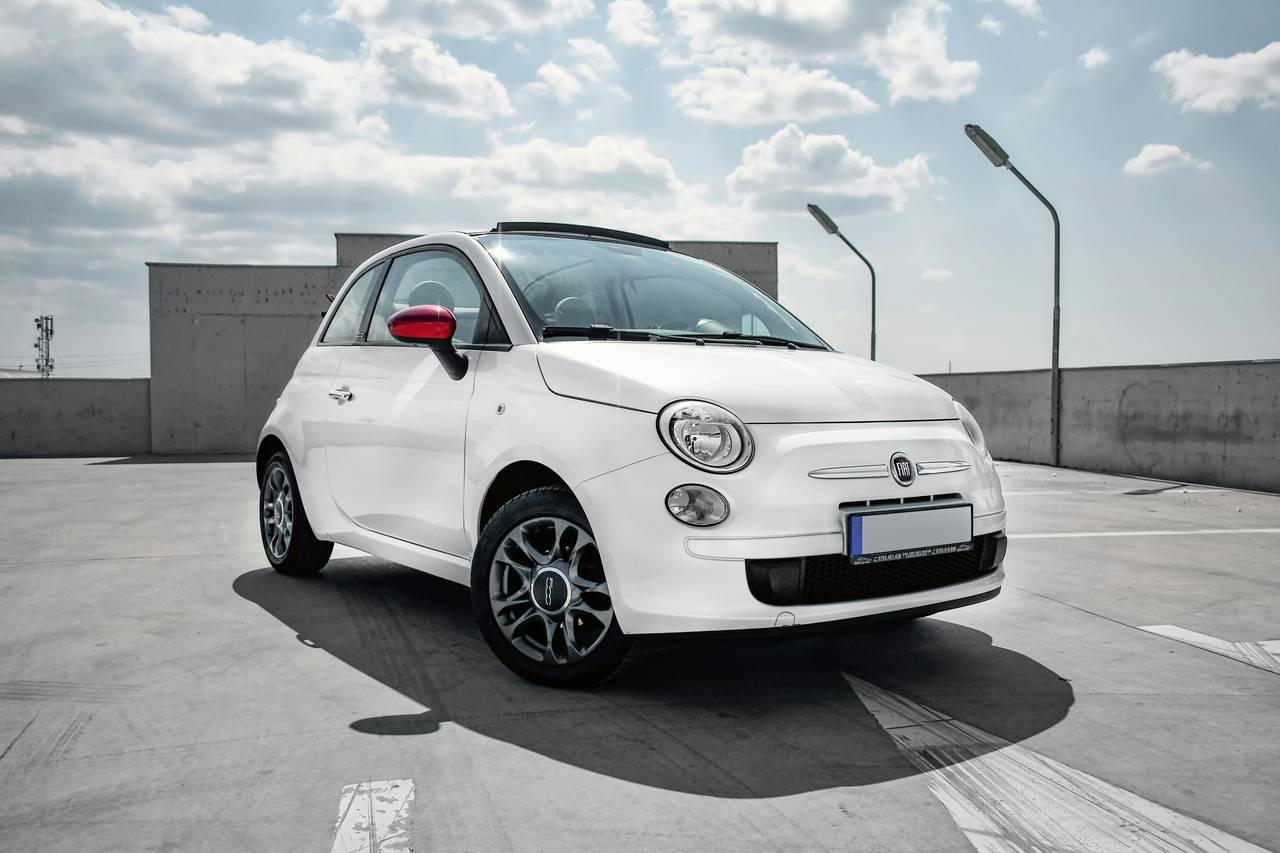 Weisser Fiat 500C mit offenem Stoffverdeck auf einem Parkdeck
